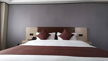 Een moderne hotelkamer met een groot bed, een hoofdbord, nachtkastjes en een nachtkastje met een telefoon.