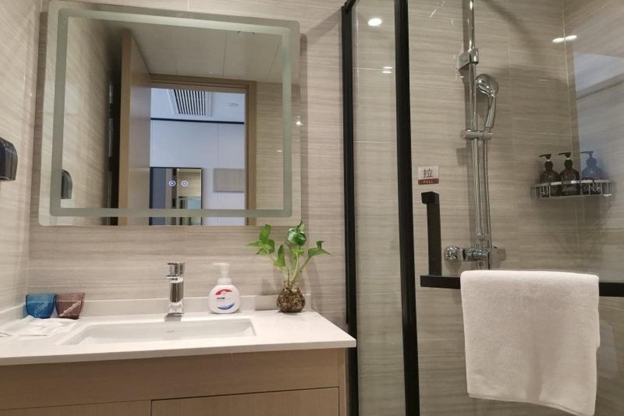 A modern bathroom with a glass shower enclosure, a sink with a mirror, and toiletries.