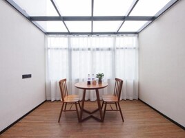 Una habitación con una mesa redonda y cuatro sillas, una ventana con cortinas translúcidas y un tragaluz.