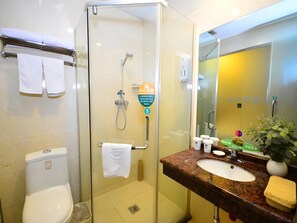 A bathroom with a glass-enclosed shower, a white toilet, a sink with a granite countertop, and a mirror with a yellow wall. - Greentree Inn Xuzhou Yunlong District West Gate of Yunlong Public Park Express Hotel (Xuzhou)