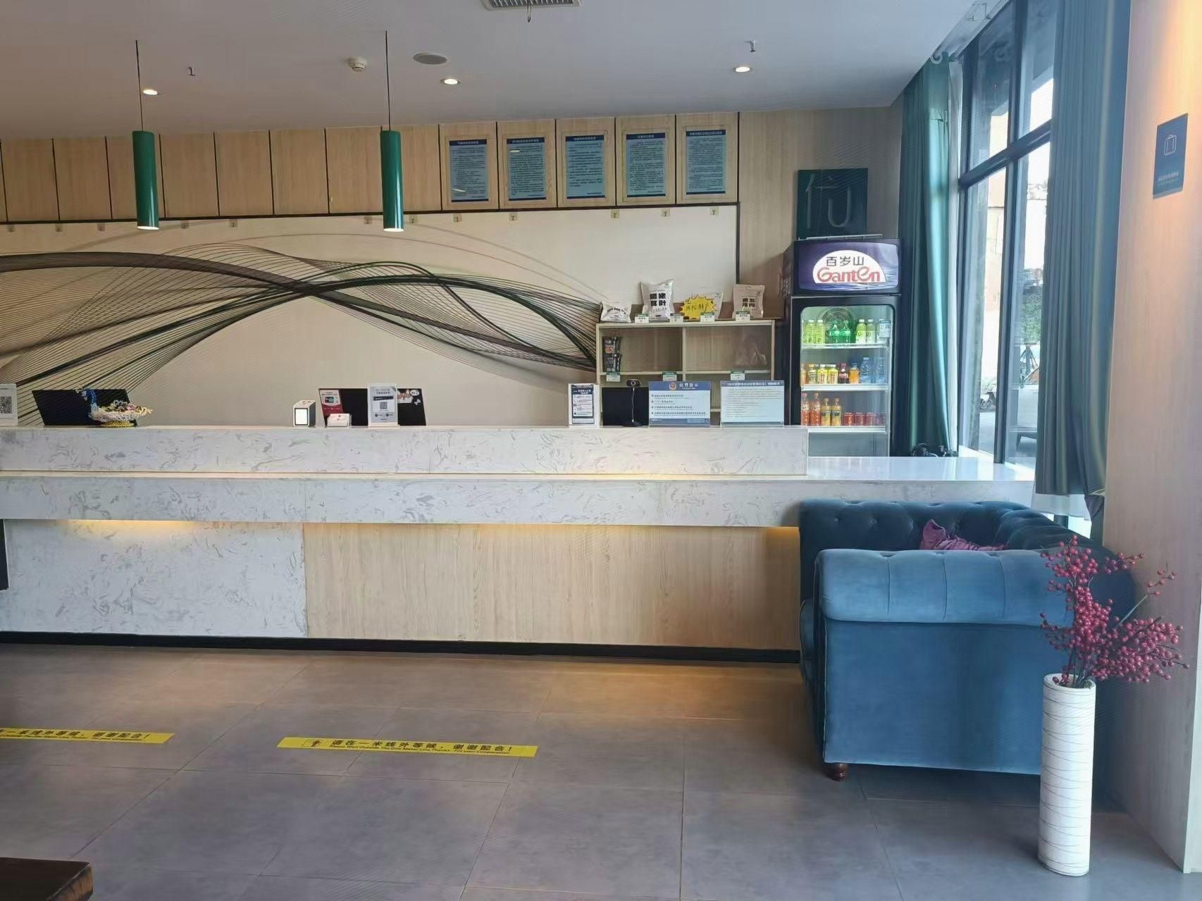 A reception area with a counter, a blue sofa, a decorative vase, and a beverage refrigerator.