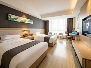 Habitación de hotel con dos camas, un escritorio, una silla y un televisor.