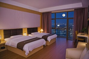 A hotel room with two beds, a desk, and a view of the city at night. - Rongzhou Hotel (Yulin)