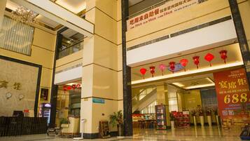 A hotel lobby with a reception desk, a chandelier, and red lanterns.