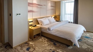 A hotel room with a large bed, bedside tables, a wall-mounted TV, and a window with curtains. - Metropolo Jinjiang Hotels (Xuzhou)