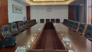 A conference room with a long table, multiple chairs, and a logo on the wall. - Metropolo Jinjiang Hotels (Xuzhou)