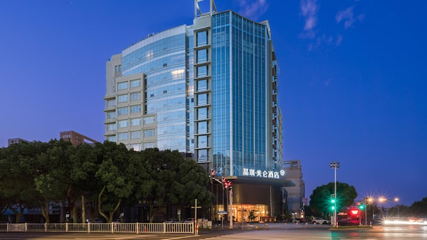 Un hôtel moderne doté d’une façade en verre, de plusieurs étages et d’une entrée imposante.