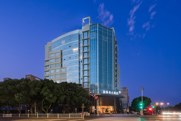 Un hotel moderno con fachada de vidrio, varios pisos y una entrada destacada.