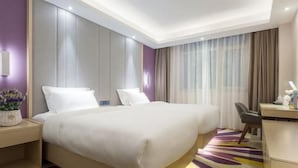 A hotel room with a large bed, a desk, and a chair. - Lavande Hotel (Beijing)