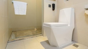 A bathroom with a toilet, a towel hanging on the wall, and a shower area. - Lavande Hotel (Beijing)