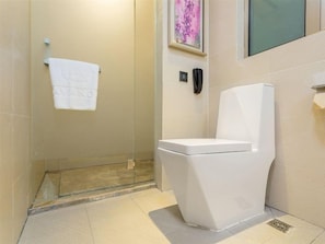 A bathroom with a toilet, a towel hanging on the wall, and a shower area. - Lavande Hotel (Beijing)
