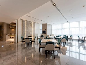 Et moderne mødelokale på et hotel med en skinnende marmorbelægning, et centralt bord og flere stole.