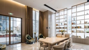 A modern conference room with a large table, comfortable chairs, and a bookshelf filled with books. - Atour Hotel Yiwu International Trade City Passenger Transport Center (Jinhua)