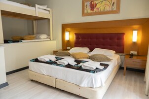 Una habitación de hotel con una cama, mesitas de noche, un espejo y un cuadro en la pared.