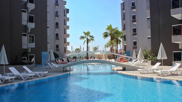 Una piscina amb gandules i ombrel·les, envoltada d'edificis alts.
