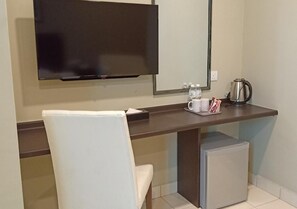 Un espai d'oficina petit amb escriptori, cadira, televisió i cafetera.