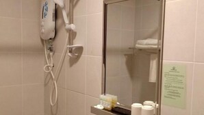 A bathroom with a hairdryer, a mirror, and a shelf with toiletries. - Hotel Desaru Penawar (Bandar Penawar)