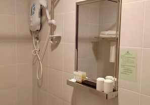 A bathroom with a hairdryer, a mirror, and a shelf with toiletries. - Hotel Desaru Penawar (Bandar Penawar)