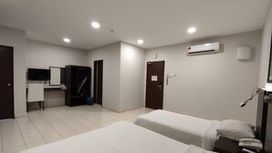 A hotel room with two beds, a desk, a chair, a TV, and an air conditioning unit. - Hotel Desaru Penawar (Bandar Penawar)
