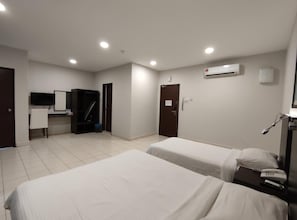 A hotel room with two beds, a desk, a chair, a TV, and an air conditioning unit. - Hotel Desaru Penawar (Bandar Penawar)