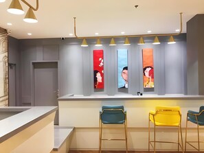 A modern bar area with a counter, three chairs, and wall-mounted artwork. - Magnotel (Harbin)