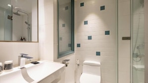 A modern bathroom with a glass shower enclosure, a white sink with a mirror, and a toilet. - Magnotel (Harbin)