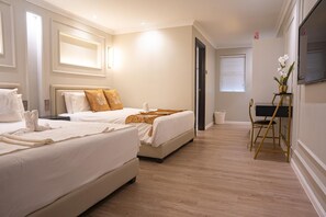 A hotel room with two beds, a desk, and a chair. - White Mansion Hotel (George Town)