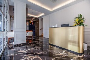A hotel reception area with a marble floor, a reception desk, and a staircase leading to another floor. - White Mansion Hotel (George Town)