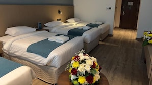 Habitación de hotel con dos camas, una mesita de noche, una lámpara de pared y una puerta.