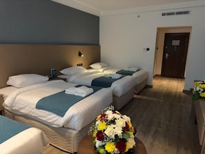 A hotel room with two beds, a bedside table, a wall-mounted lamp, and a door. - Grand Al Massa Hotel (Makkah)