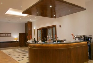 A reception area with a wooden reception desk, a coffee machine, and a wall-mounted clock. - Grand Al Massa Hotel (Makkah)