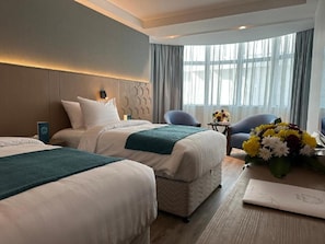 A hotel room with two beds, a small table with a vase of flowers, and a seating area with chairs. - Grand Al Massa Hotel (Makkah)