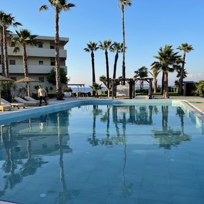 Una piscina con palmeras y un edificio al fondo.