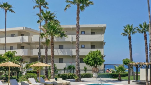 A hotel with a swimming pool, palm trees, and lounge chairs. - Ixia Dream - Adults Only (Rhodes)
