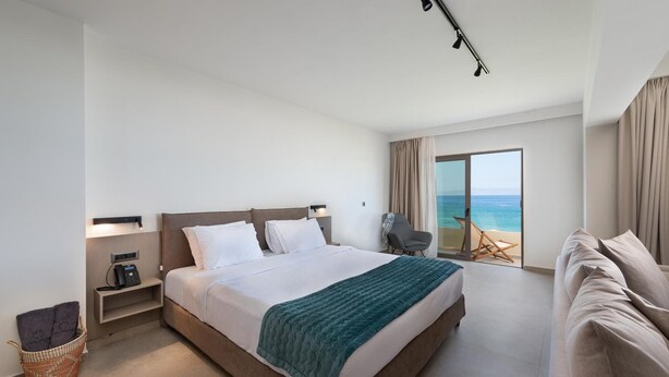 Habitación de hotel con cama, escritorio, silla y vista al mar.