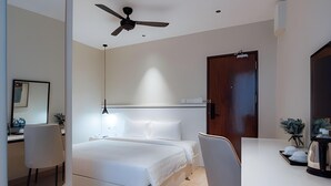 Habitación de hotel moderna con cama, escritorio, silla, ventilador de techo y puerta.