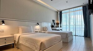 A hotel room with two beds, a bedside table, a lamp, and a window with curtains. - Grace Samudera Hotel Semporna (Semporna)