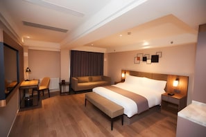 Una habitación de hotel moderna con una cama grande, un sofá, un escritorio y una silla.