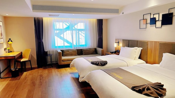 A hotel room with two beds, a sofa, a desk with a chair, and a large window with curtains. - Homeinns Plus Longhua Road Qiqihar (Qiqihar)