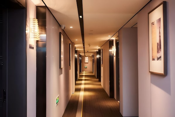 A long, narrow hotel corridor with a wooden floor and walls on either side.
