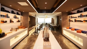 Un hall d’hôtel moderne avec une allée centrale, un espace détente et des étagères où sont exposés divers objets.