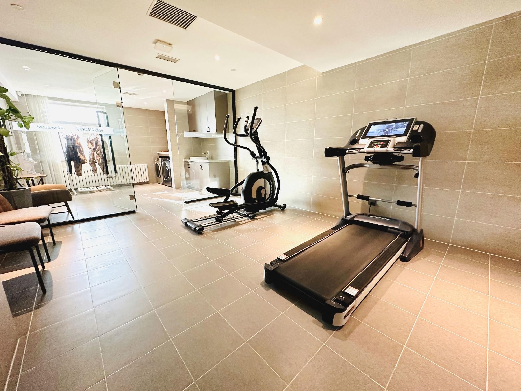 A gym with a treadmill, exercise bike, and a mirrored wall.