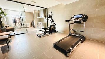 A gym with a treadmill, exercise bike, and a mirrored wall.