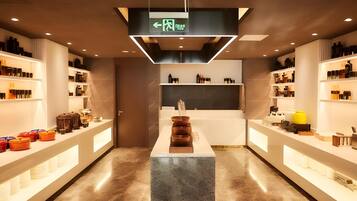 A modern interior with a central island, shelves on both sides, and a ceiling sign indicating an exit.