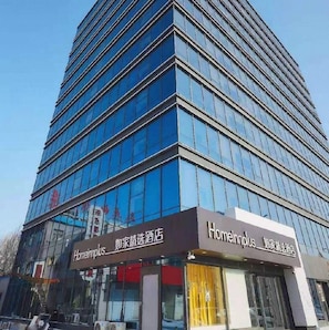 Hotel moderno com fachada de vidro e sinalização em inglês e chinês.