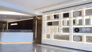 Un hall d’hôtel moderne avec un comptoir d’accueil, un mur décoré d’instruments de musique et un sol ciré.