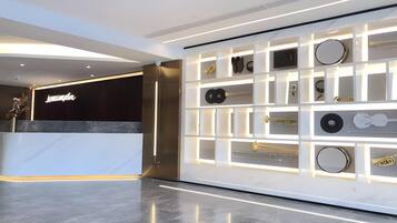 A modern hotel lobby with a reception desk, a wall of musical instruments, and a polished floor.