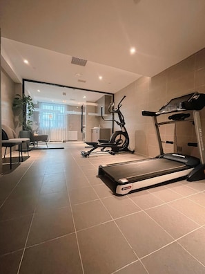 A modern home gym with a treadmill, stationary bike, and exercise mat.