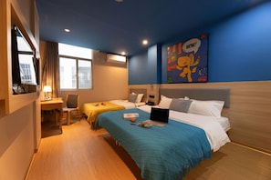 Habitación de hotel con dos camas, un escritorio, una silla y un ventanal grande.
