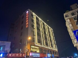 A multi-story hotel with illuminated signage, a ground-level restaurant, and a pedestrian crossing sign. - Homeinn Selected (Guangzhou)